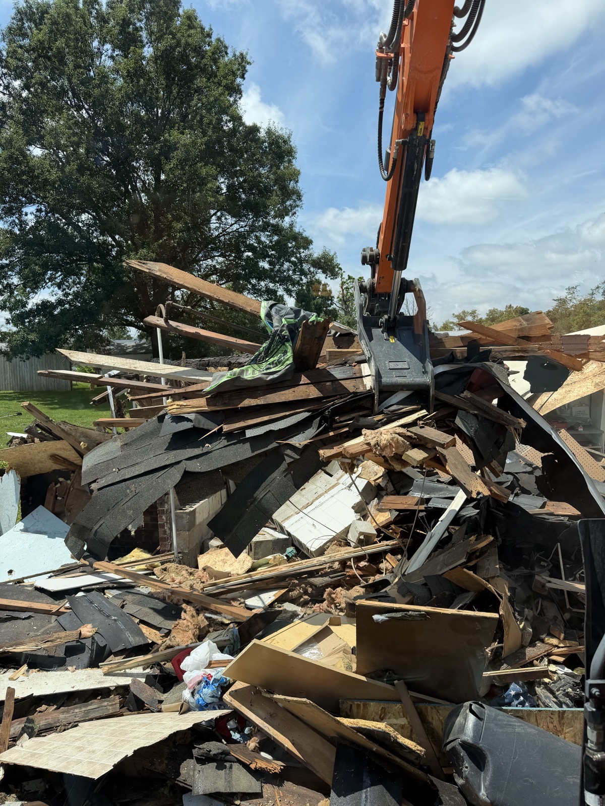 Excavator grapple working the debris pile of a torn-down house and attached garage in Charleston, IL — Brohez Trucking LLC