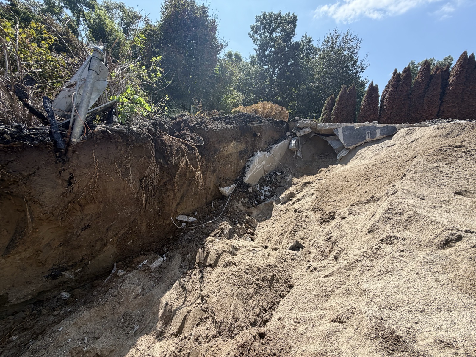 Excavated basement wall face with sand piled alongside on a concrete removal job in Mattoon, IL — Brohez Trucking LLC