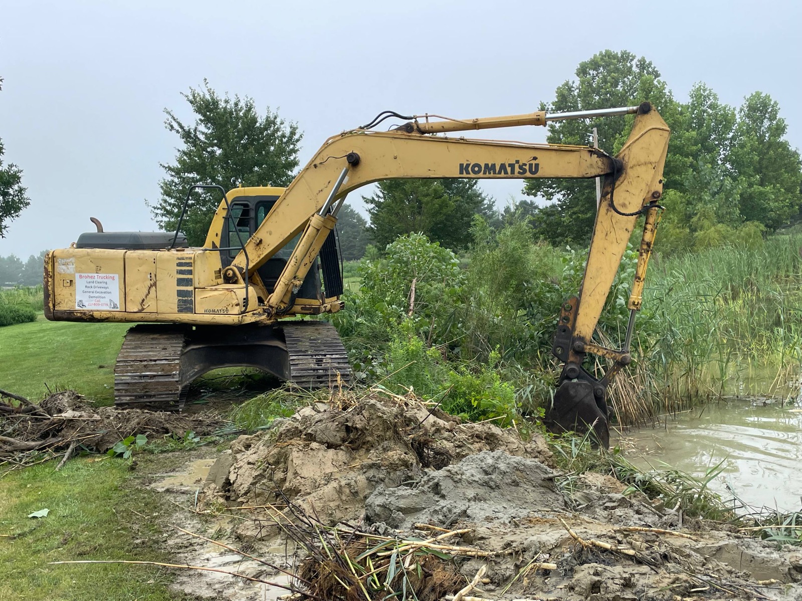 Komatsu excavator set up on the pond bank at the start of a cleanout in central Illinois — Brohez Trucking LLC