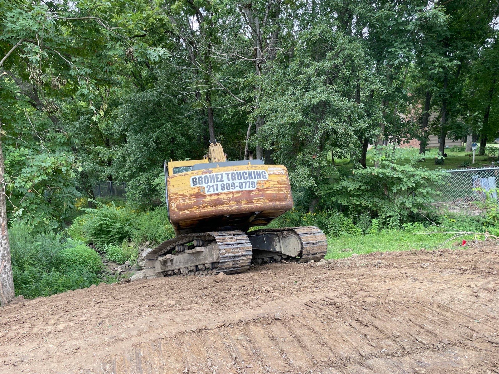 Brohez Trucking excavator sitting on the rebuilt crest of a repaired pond dam near Decatur, Illinois