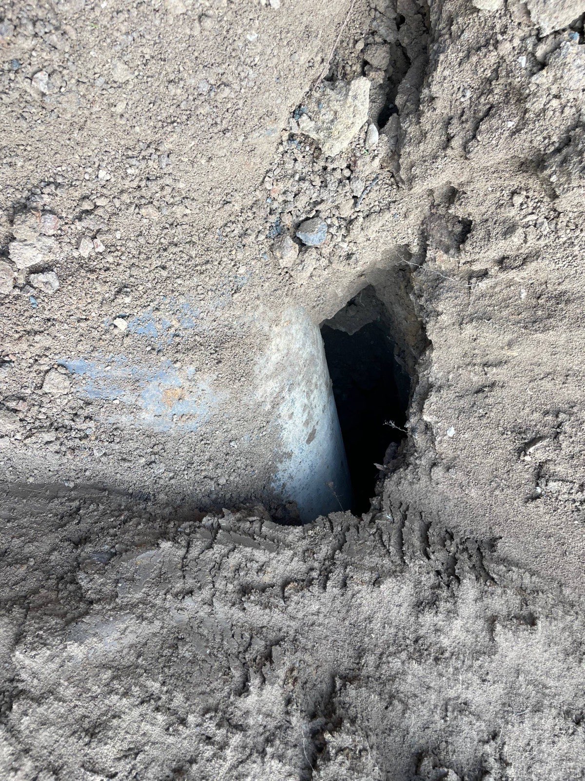 An open piping void tunnelled through a pond dam alongside the galvanized outlet pipe, exposed during a dam repair near Decatur, Illinois — Brohez Trucking LLC